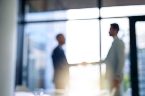 Insurance 101: Insurance Basics Blurry image of an office with two men shaking hands